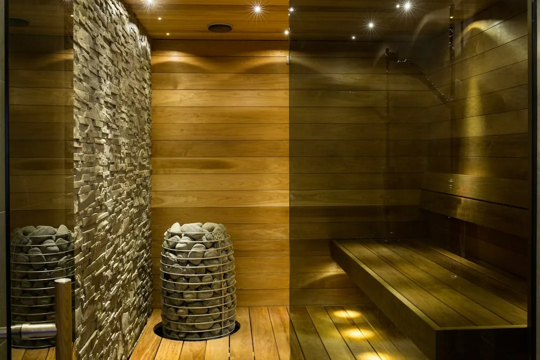 Illustrative wooden sauna benches beside a stone-filled heater