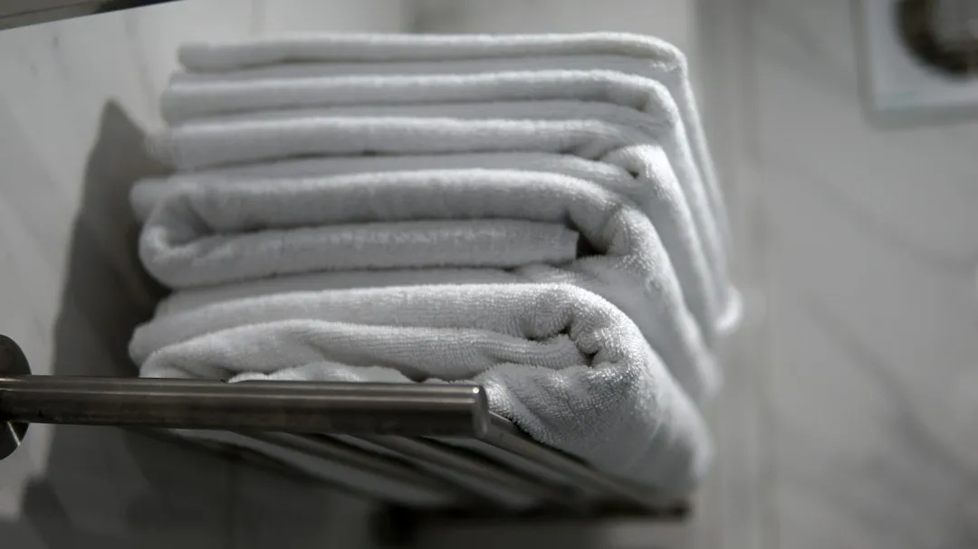 Illustrative stack of folded white towels on a metal rack