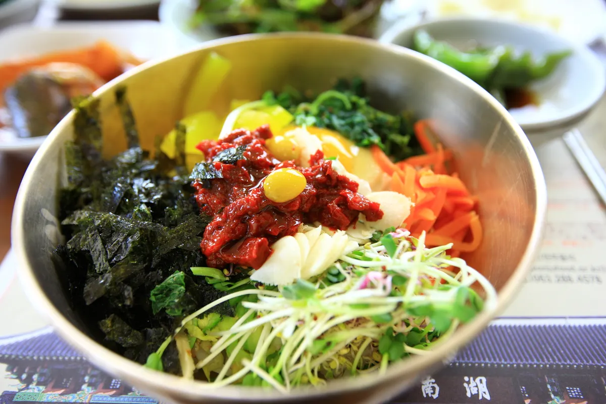 Jeonju bibimbap served with arranged vegetables and egg in a bibimbap guide