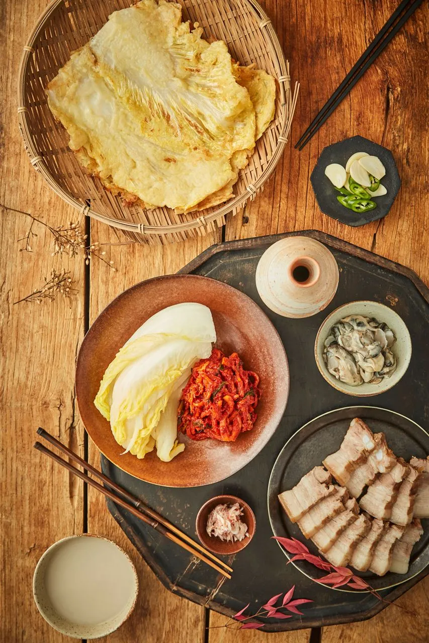 Bossam set with sliced pork, cabbage leaves, kimchi, and side dishes