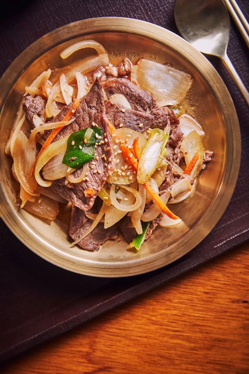 Bulgogi served in a shallow bowl with vegetables and broth