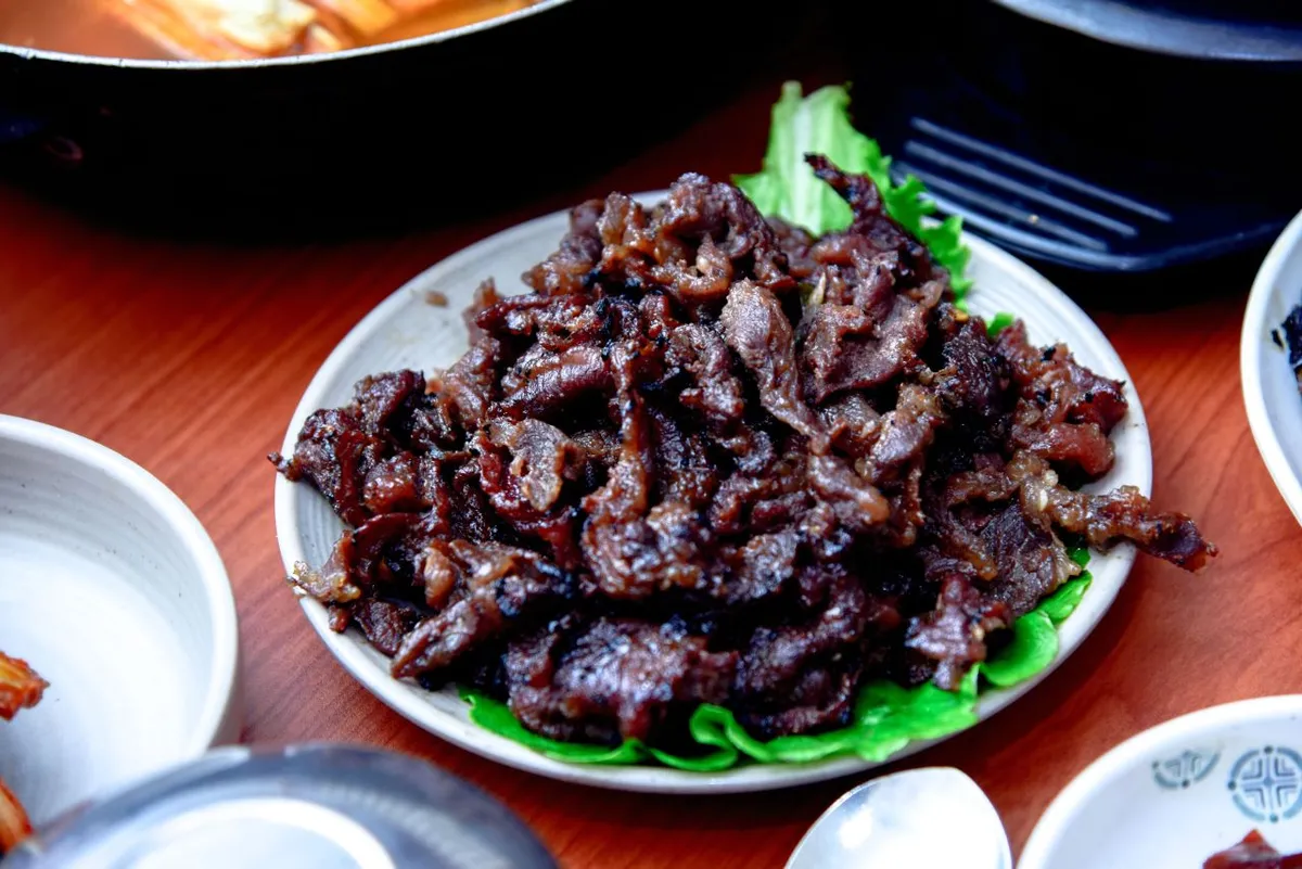 Cooked bulgogi beef served on lettuce with Korean side dishes