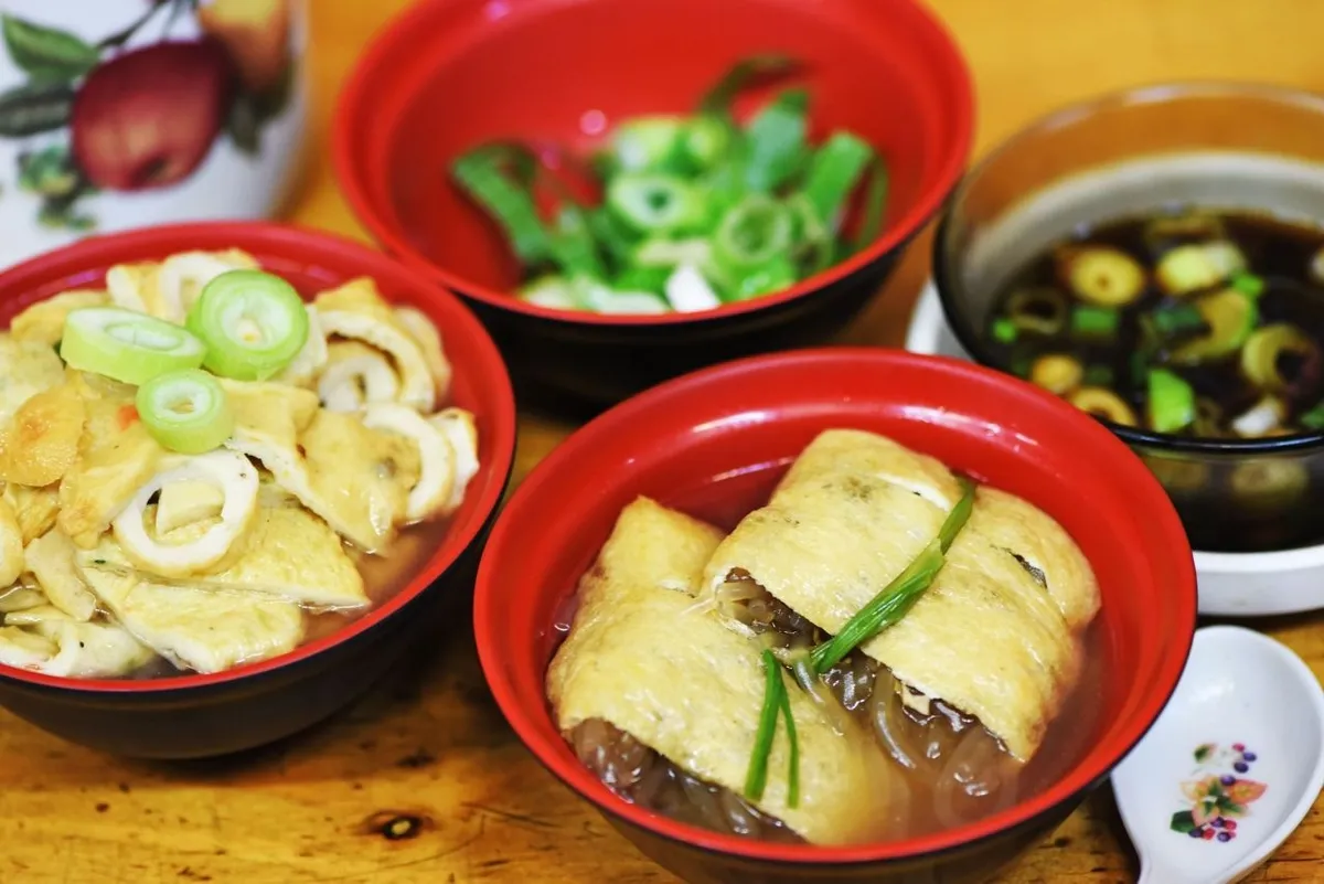Tied yubu jumeoni tofu pockets with glass noodles beside fish-cake broth at Bupyeong Market