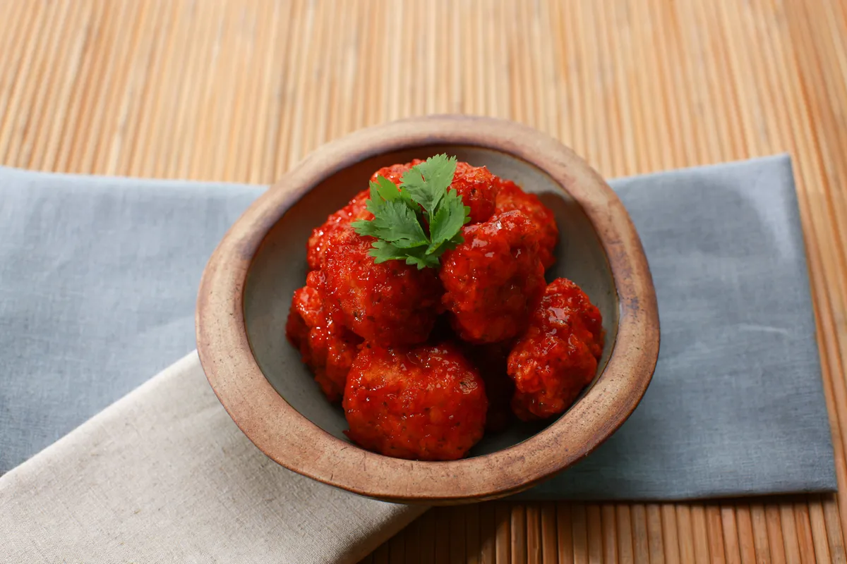 Dakgangjeong glazed chicken pieces in a bowl for Korean chicken snacks