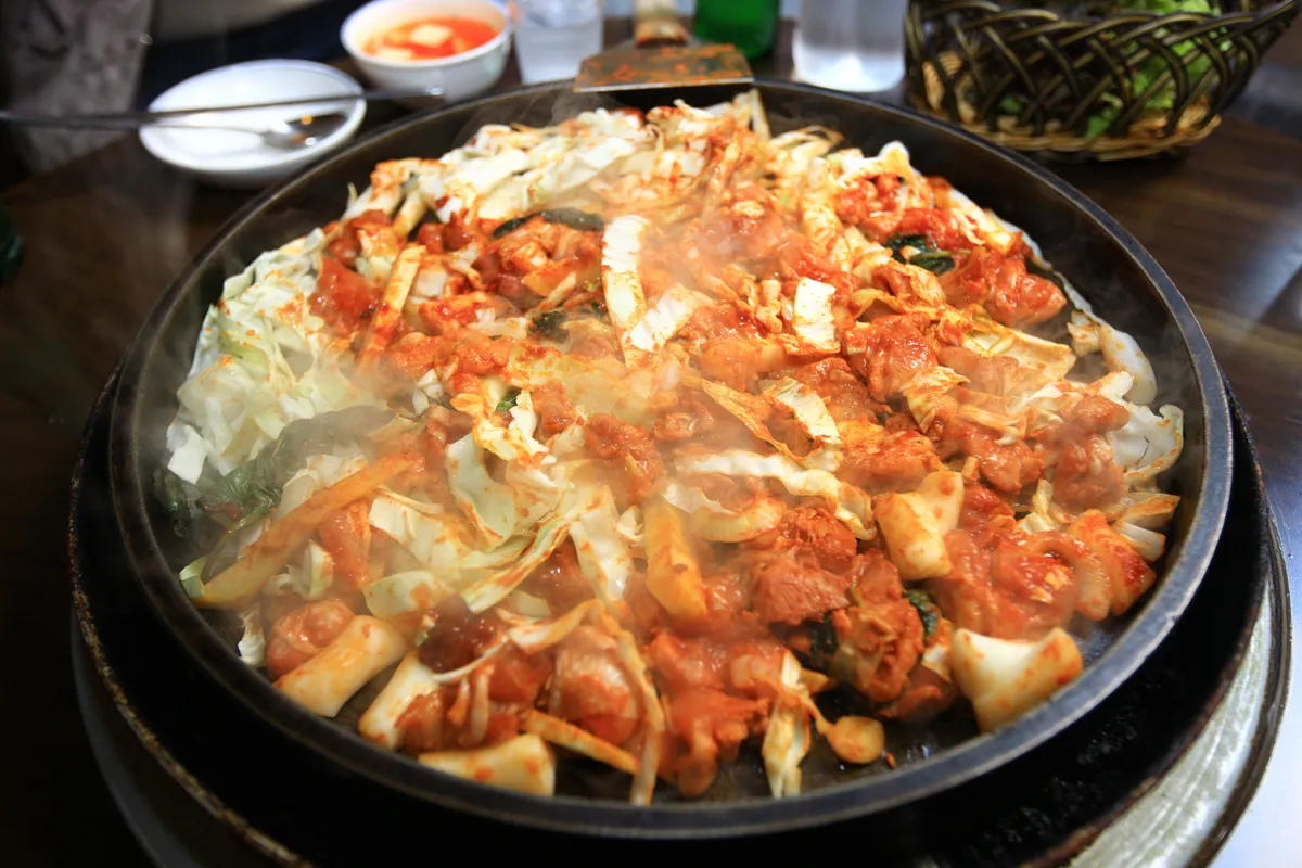 Seasoned chicken and cabbage arranged on an iron plate for Dakgalbi
