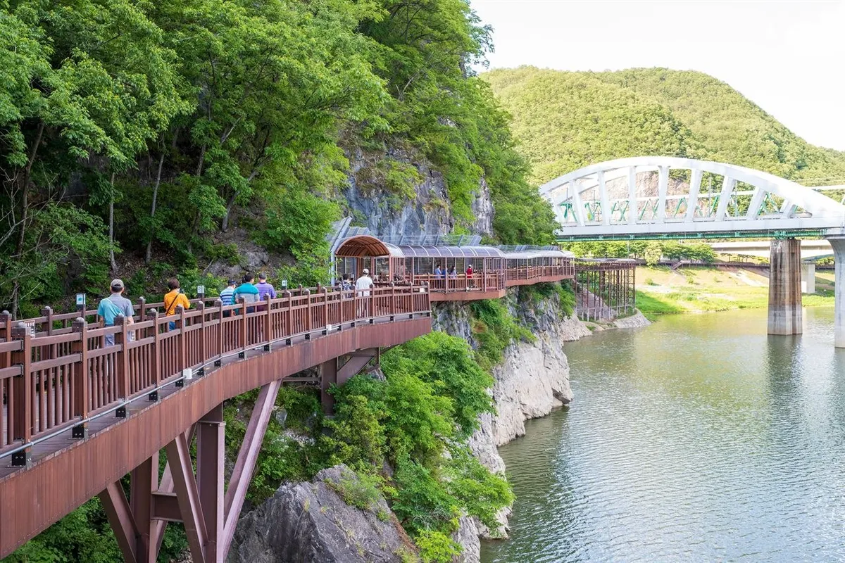 Visitors walking on Danyanggang Jando Trail beside a bridge and wooded cliff