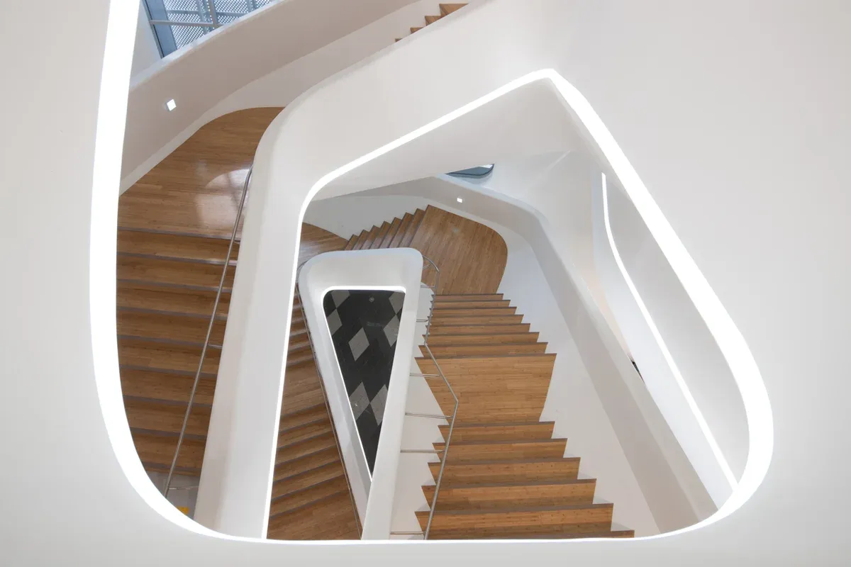 Illuminated white balustrades and wooden stairs inside Dongdaemun Design Plaza
