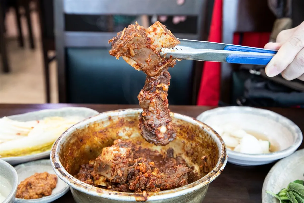 Spicy Dongin-dong jjimgalbi rib lifted from a metal bowl in Daegu