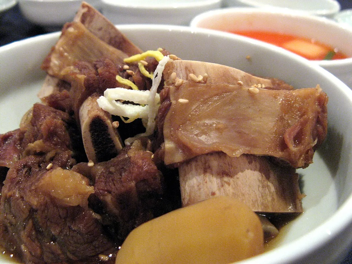 Close view of galbijjim beef rib bones with braised meat and Korean radish
