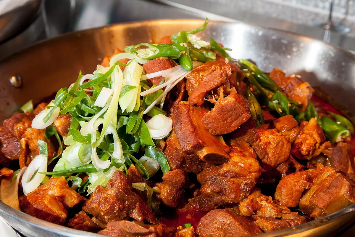 Spicy galbijjim with bone-in ribs, red sauce, green onion, and green chili
