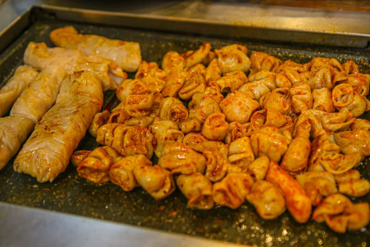Seasoned gopchang pieces cooking on a flat grill in Daegu