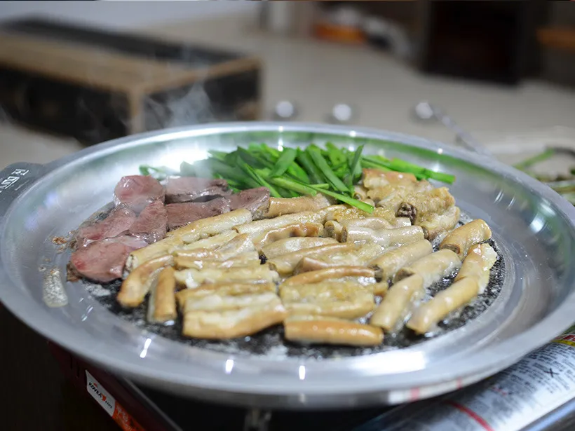 Gopchang and beef heart arranged together on a metal plate