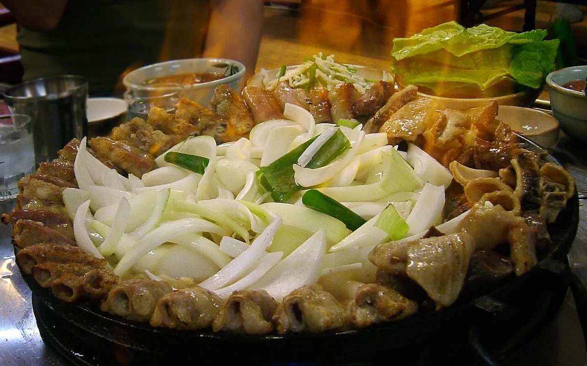Gopchang-bokkeum served on a metal pan with onions and vegetables