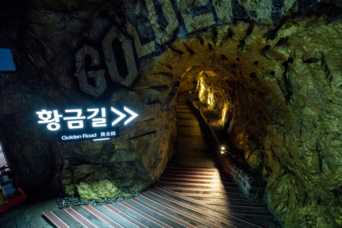 Golden Road sign beside a rock stairway inside Gwangmyeong Cave
