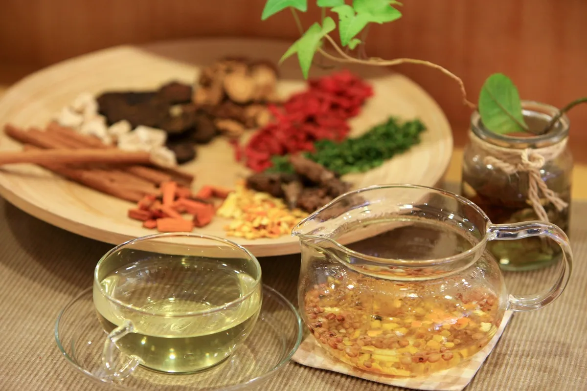 A glass pot and cup of herbal tea beside a platter of dried ingredients at Tea Therapy