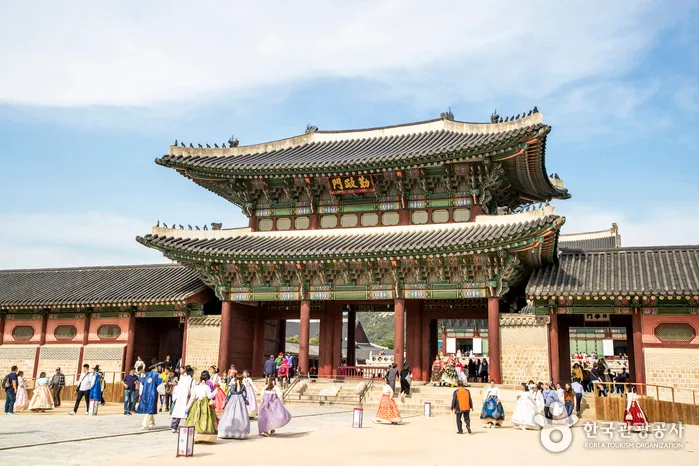 Visitors in hanbok standing before a main gate at Gyeongbokgung Palace guide