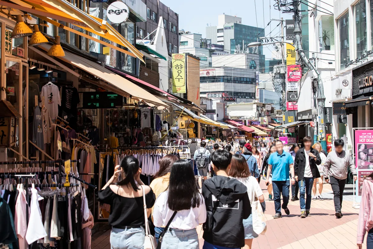 Crowded Hongdae retail street with clothing displays for Hongdae shopping route planning