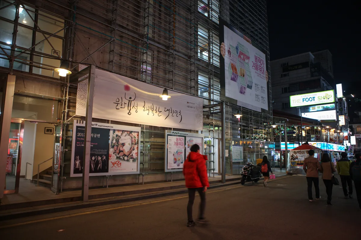Illuminated signs and poster displays outside a Daehangno theater building at night