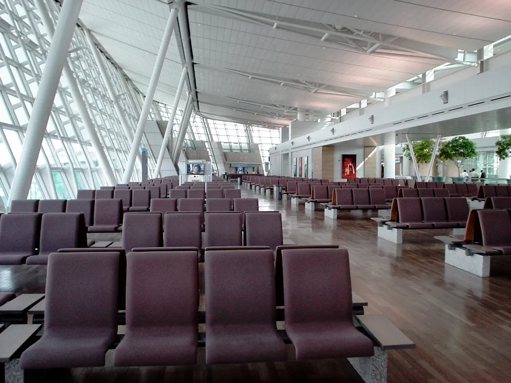 Rows of purple seats beneath the curved white ceiling in an Incheon Airport gate waiting area