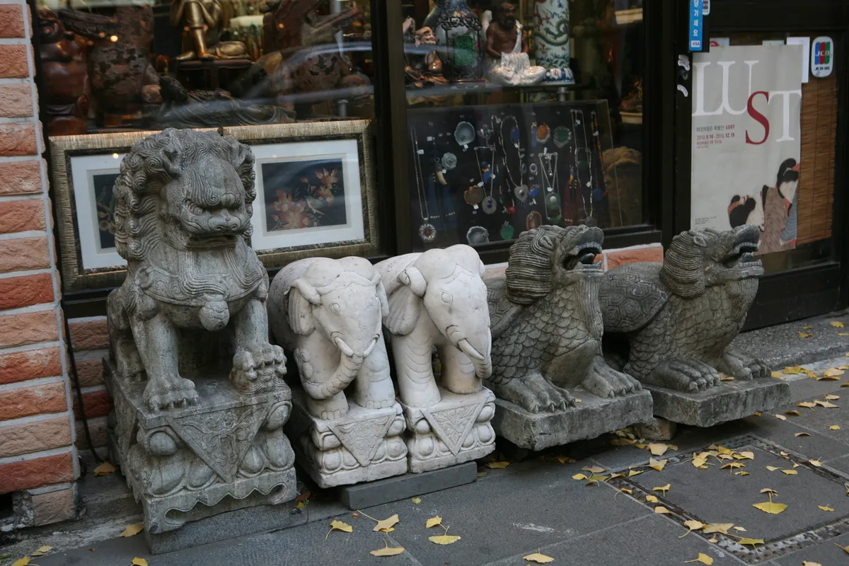 Stone sculptures and antique-style objects displayed outside an Insadong antique shop