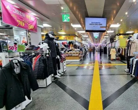 Clothing racks and Greenjoy storefront inside Jeju Jungang Underground Shopping Center