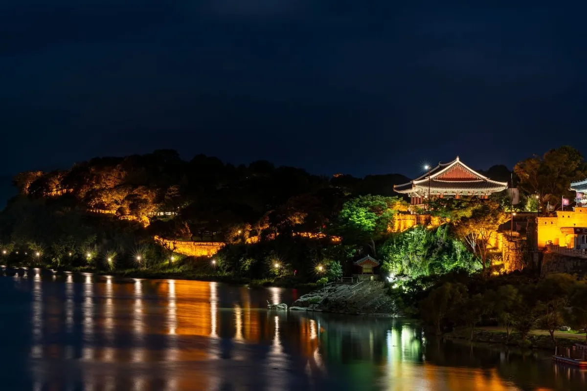 Illuminated Jinjuseong Fortress and Chokseongnu Pavilion reflected in the Namgang River at night