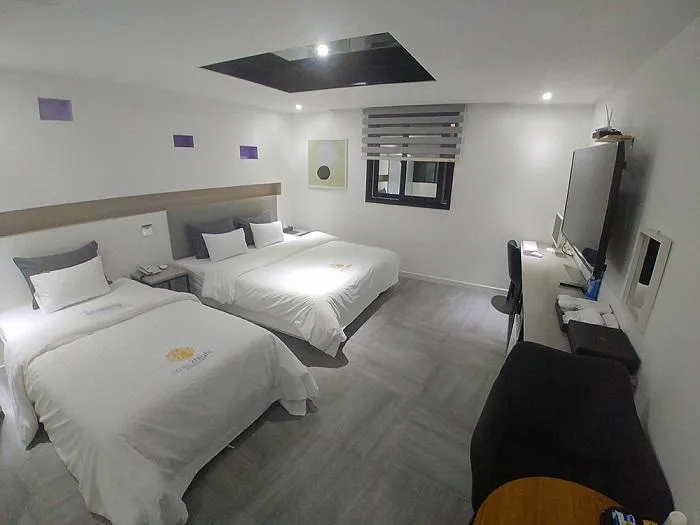 Motel room with two beds, padded headboards and a wall-mounted television