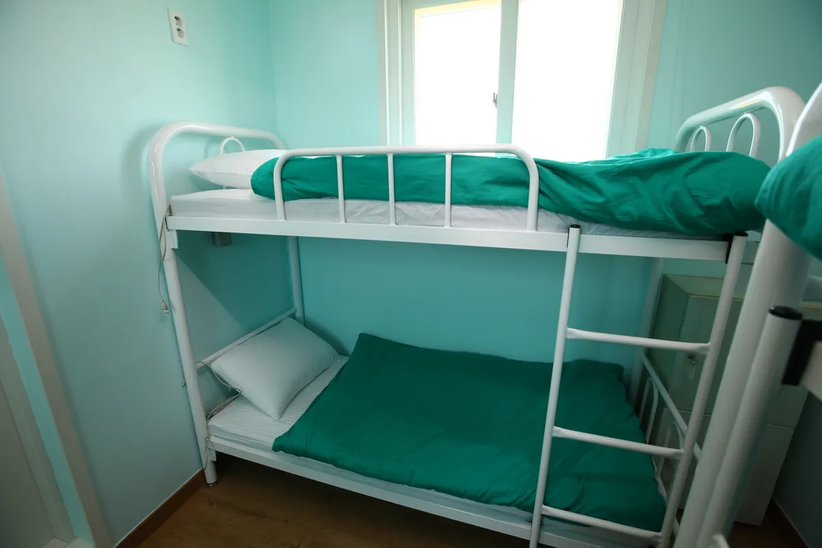 White metal bunk bed with green bedding at Guesthouse Jip, illustrating a bunk-room arrangement
