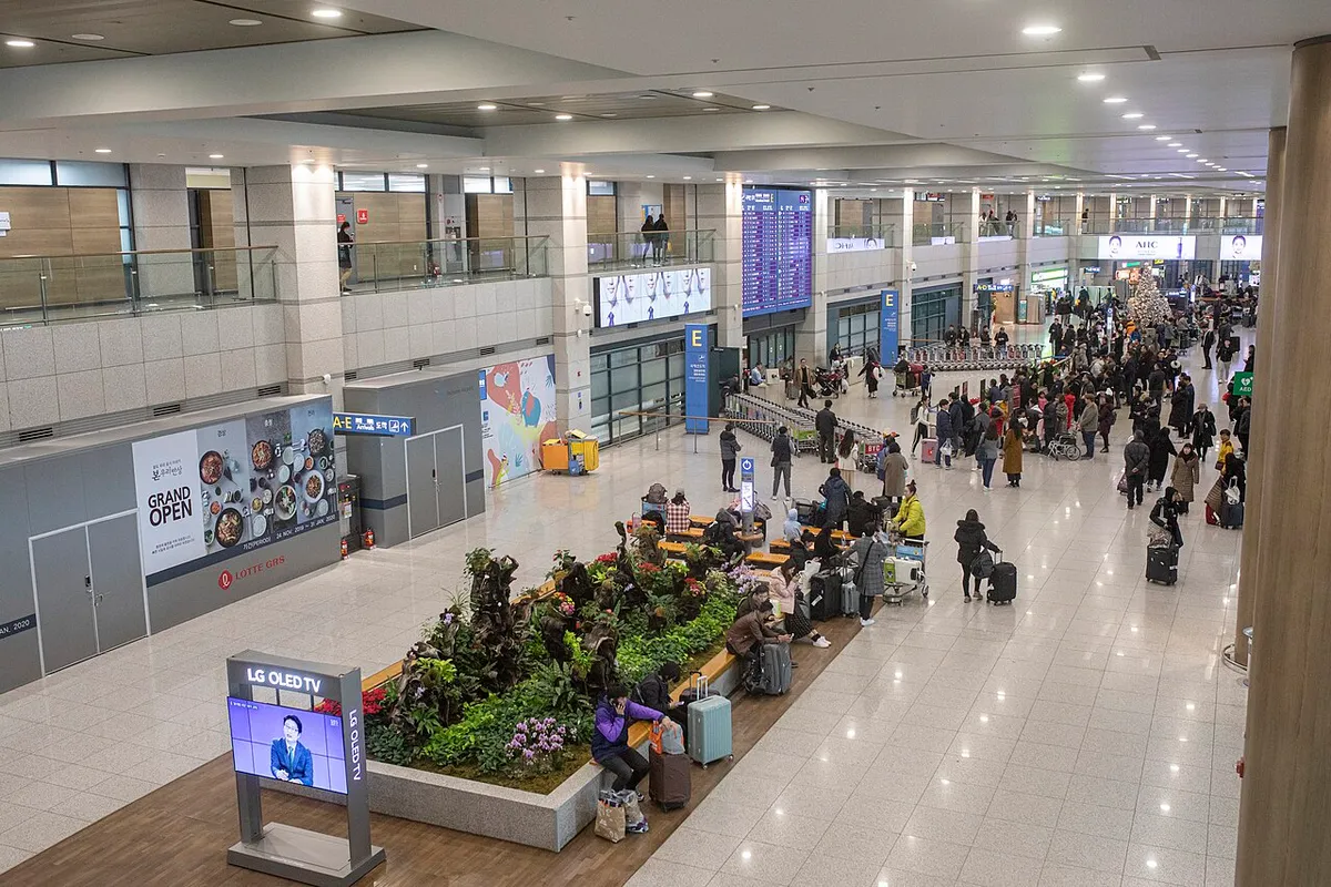 Travelers with luggage in Incheon International Airport Terminal 1 arrival hall