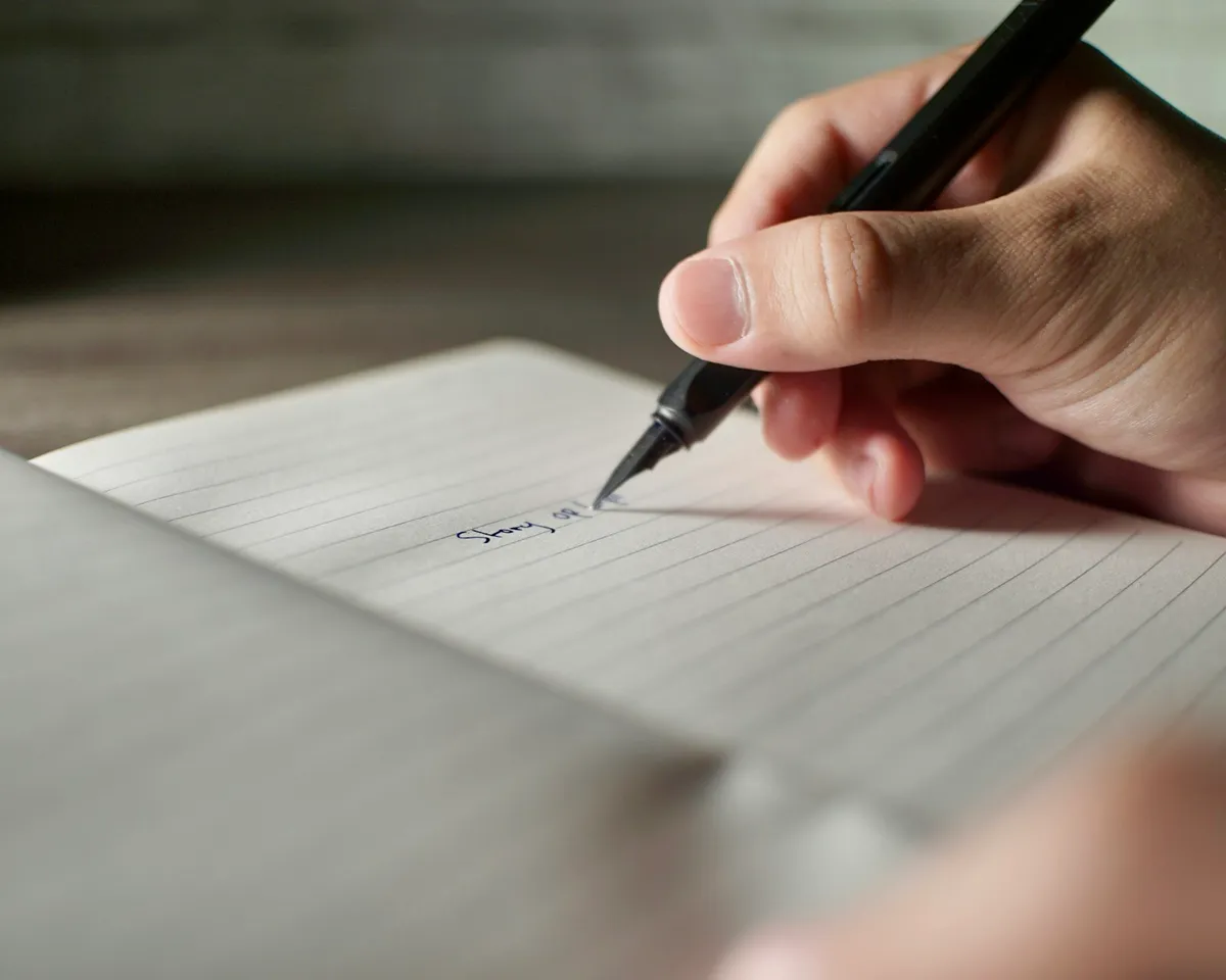 Hand writing information in a lined notebook during trip preparation