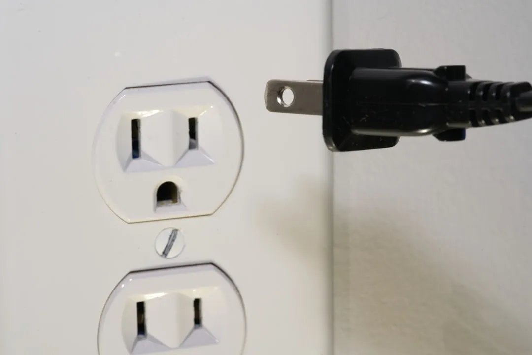Flat-prong plug beside wall outlet for Korea travel adapter planning