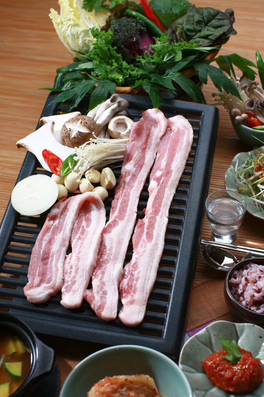 Samgyeopsal pork belly slices on a Korean barbecue grill