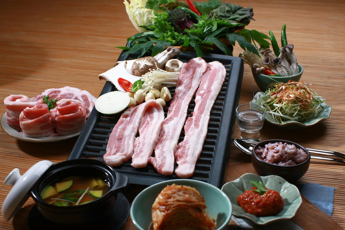 Korean barbecue table with samgyeopsal and side dishes