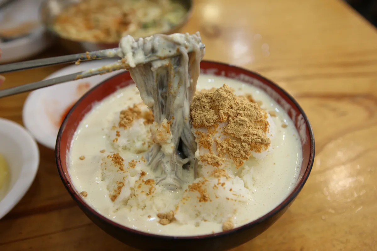 Kongguksu noodles lifted from chilled soybean broth for a Korean cold noodles guide