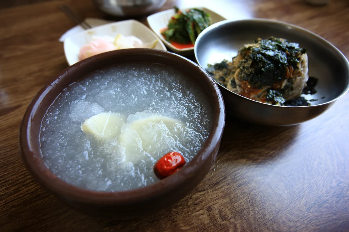 Cold makguksu broth served beside buckwheat noodles for a cold noodle guide
