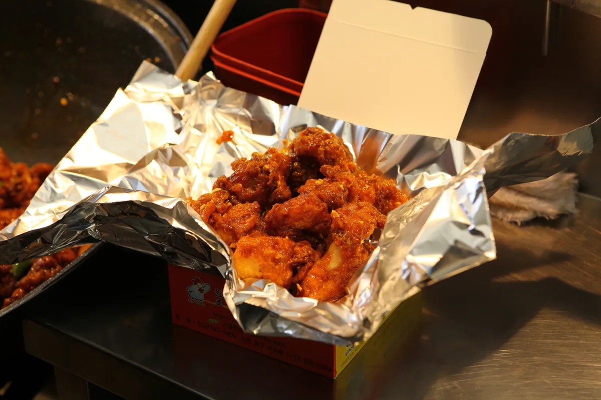 Dakgangjeong chicken served in foil packaging at a Korean market
