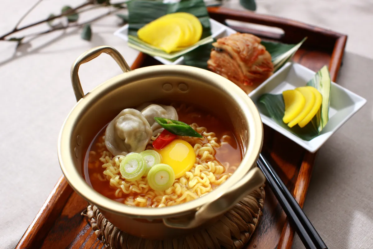 Korean ramyeon in a pot with dumplings egg and kimchi