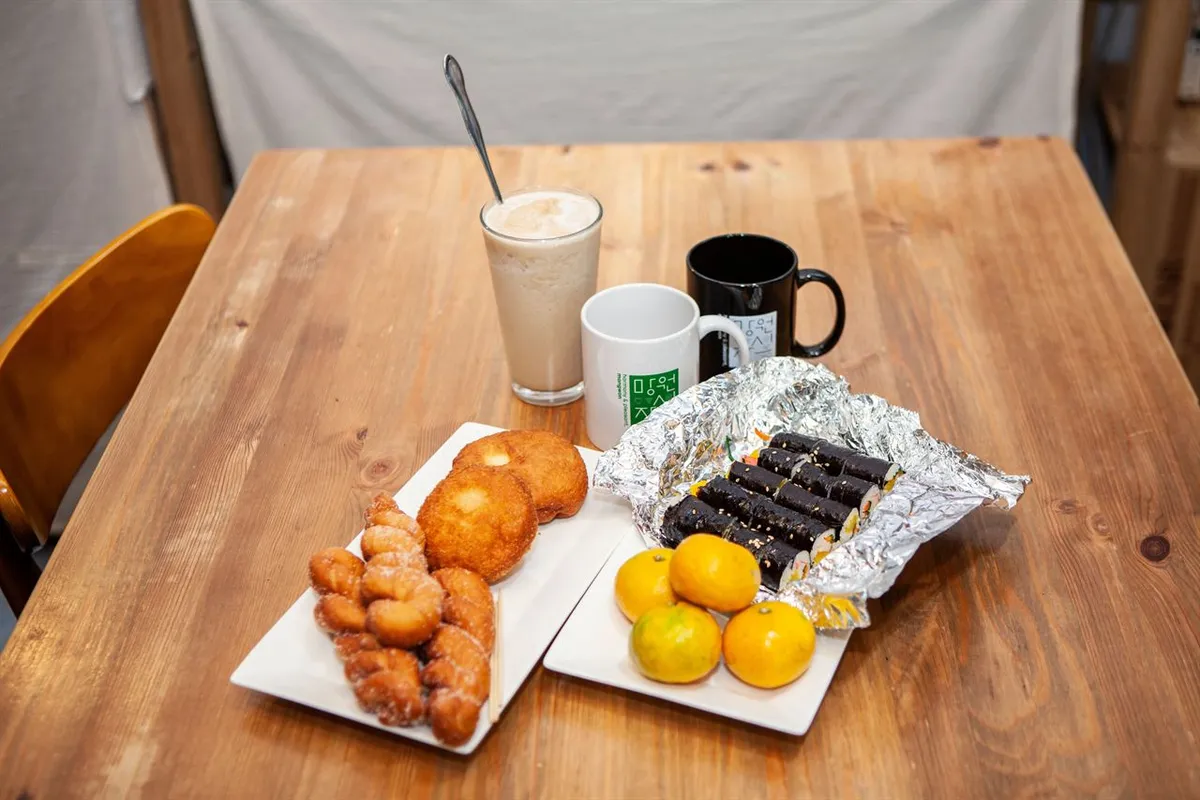 Fried pastries, sliced gimbap and small citrus fruits on a wooden table at Mangwon Market in Seoul