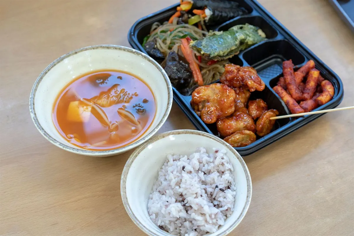 A filled compartmented Tongin Market lunchbox with separate bowls of rice and soup