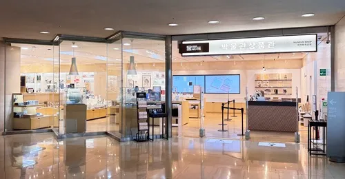 Glass-fronted Museum Shop 1 at the National Museum of Korea with illuminated displays and an entrance from the indoor concourse