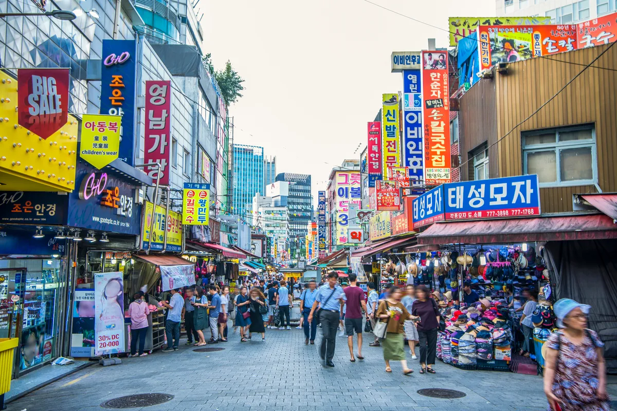 Namdaemun Market shopping street with clothing stalls, Korean signs and pedestrians near the Seoul Station district