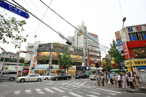 Commercial buildings, zebra crossing, and pedestrians at a Yonsei-ro intersection in Sinchon