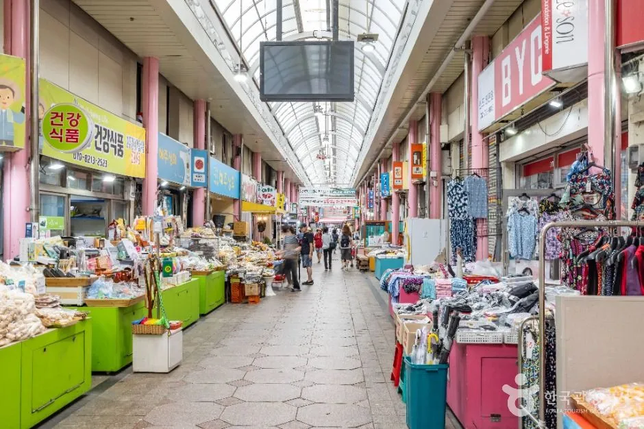 Clothing racks, produce stalls, and shoppers inside Sinpo International Market
