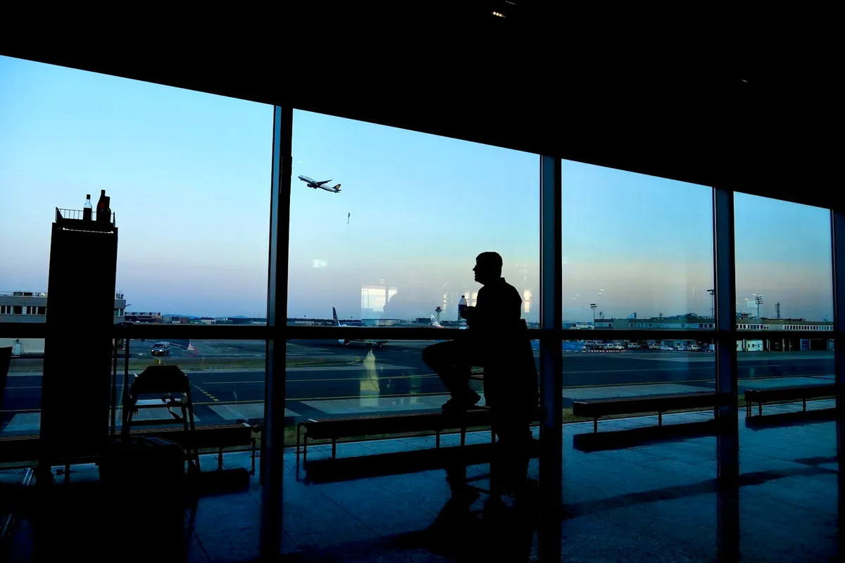 Traveler checking a phone beside an airport window before flying to South Korea