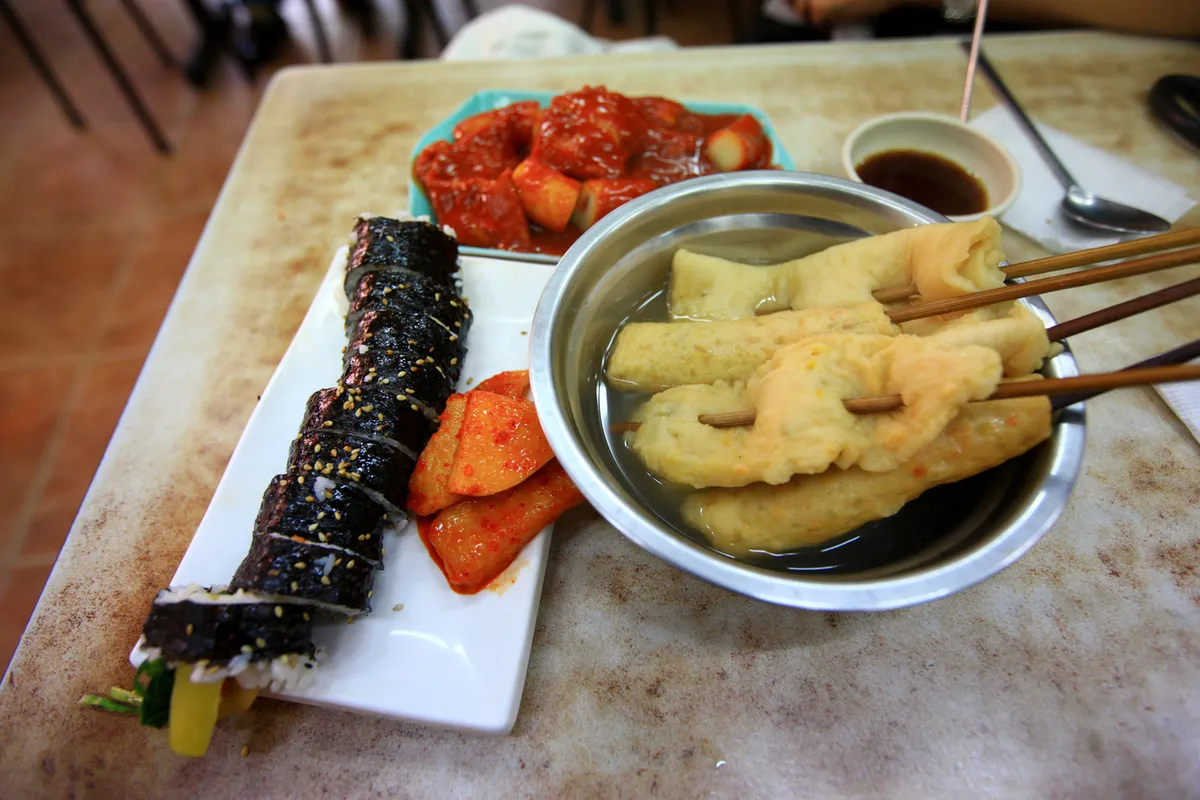 Tteokbokki fish cake and gimbap served together at a Busan street-food counter