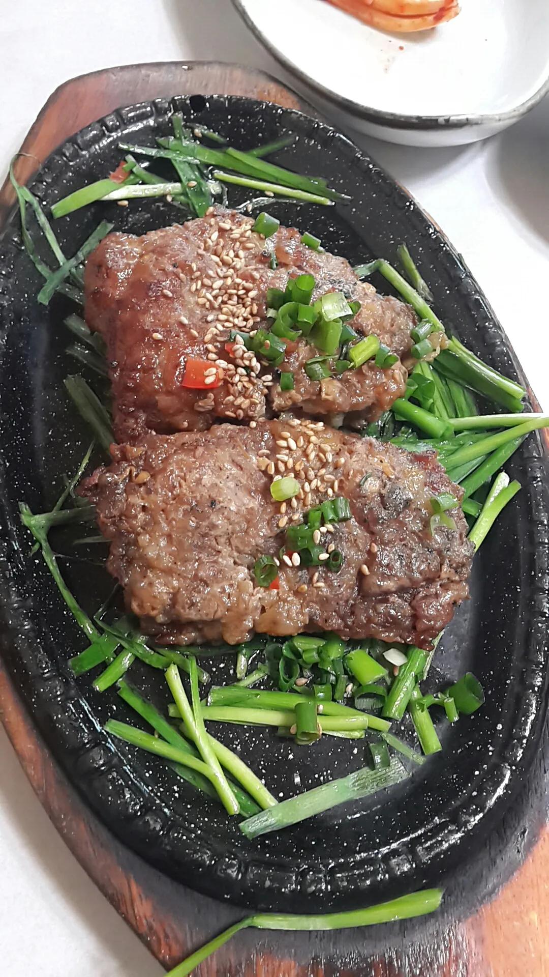Three grilled tteokgalbi patties served over green chives in Damyang
