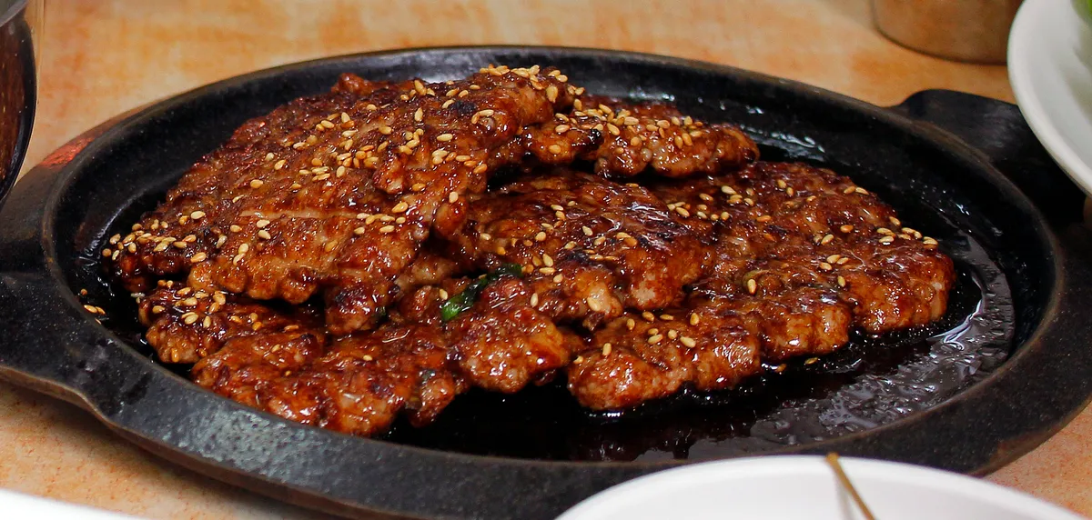 Songjeong tteokgalbi pieces served on a black hot plate