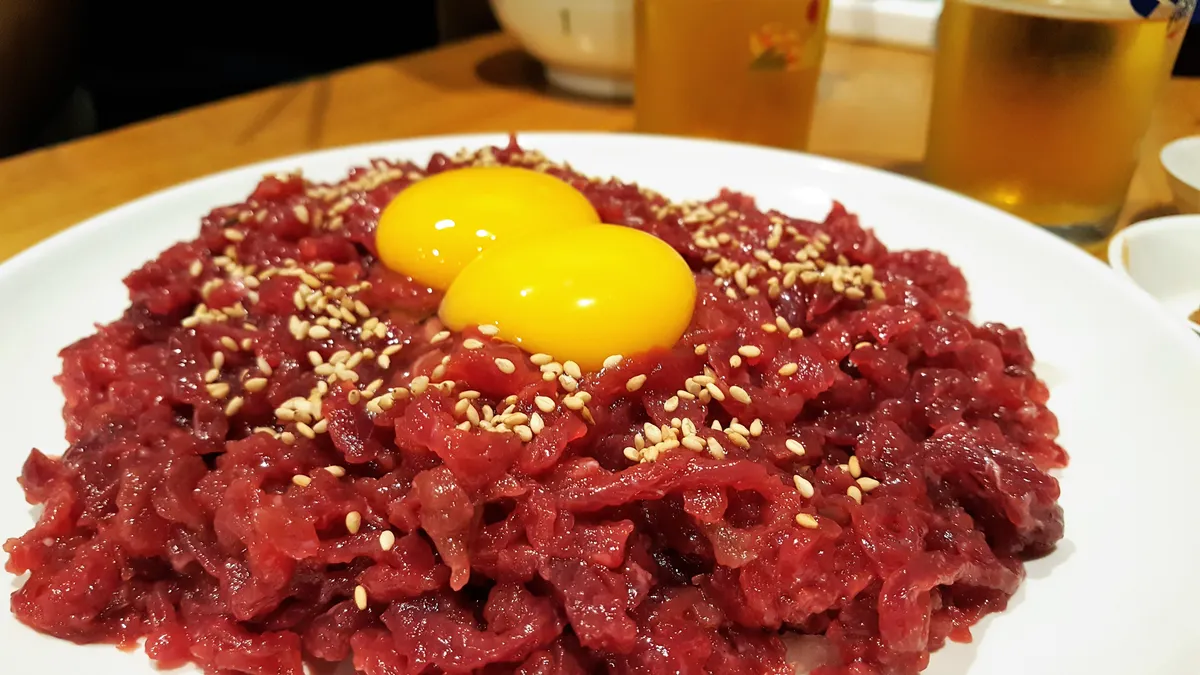 Yukhoe topped with two egg yolks and sesame seeds