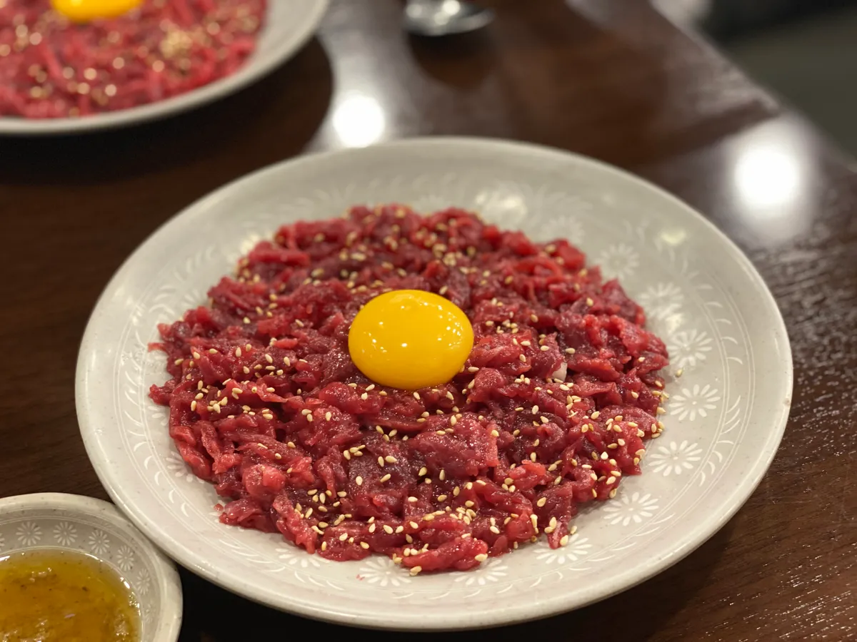 Plate of yukhoe topped with raw egg yolk and sesame seeds